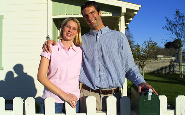 happy couple by a fenced home