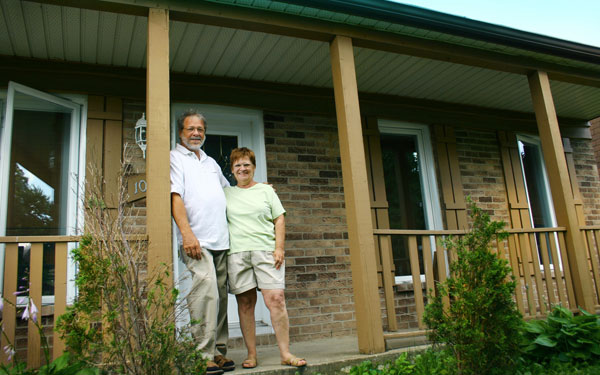 Baby boomer aged couple on the the front porch of their home Baby boomer aged couple on the the front porch of their home
